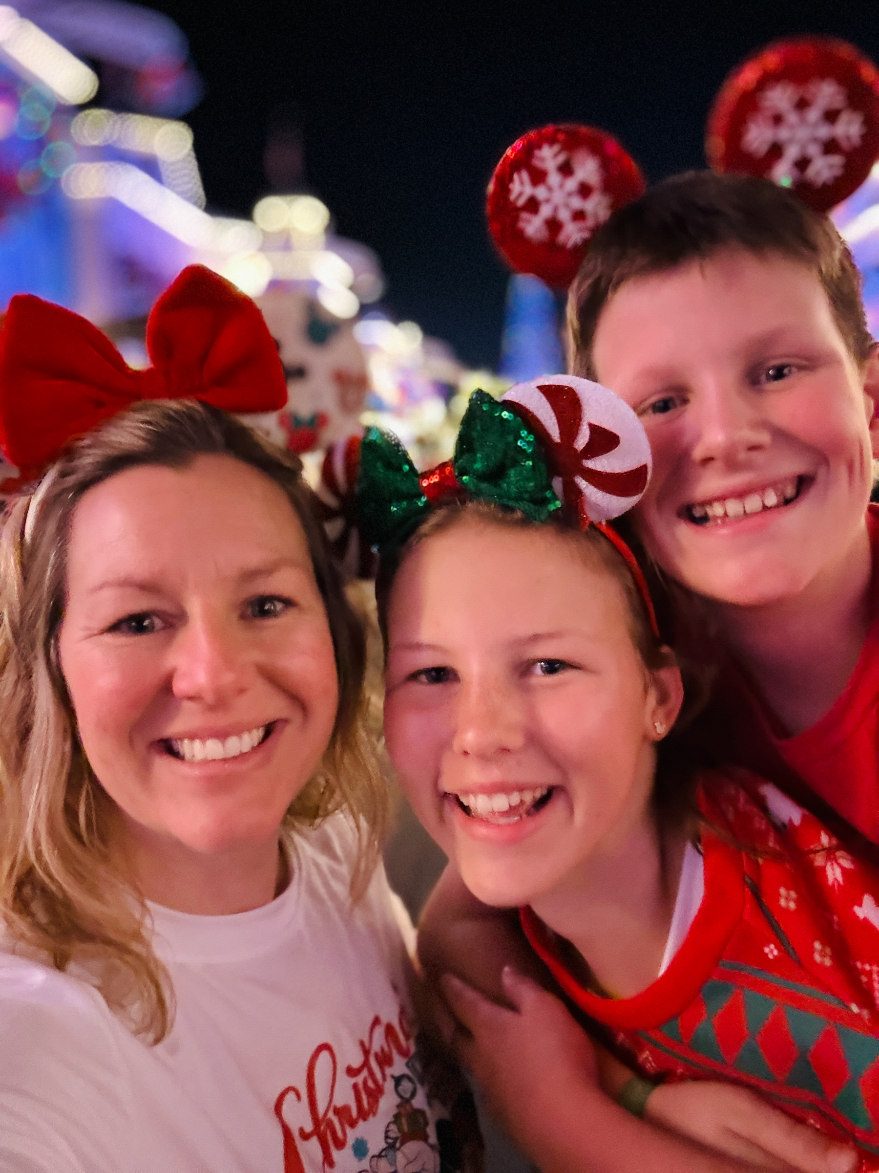 Mom and two teenagers smiling together on Main Street during Christmas at Magic Kingdom.