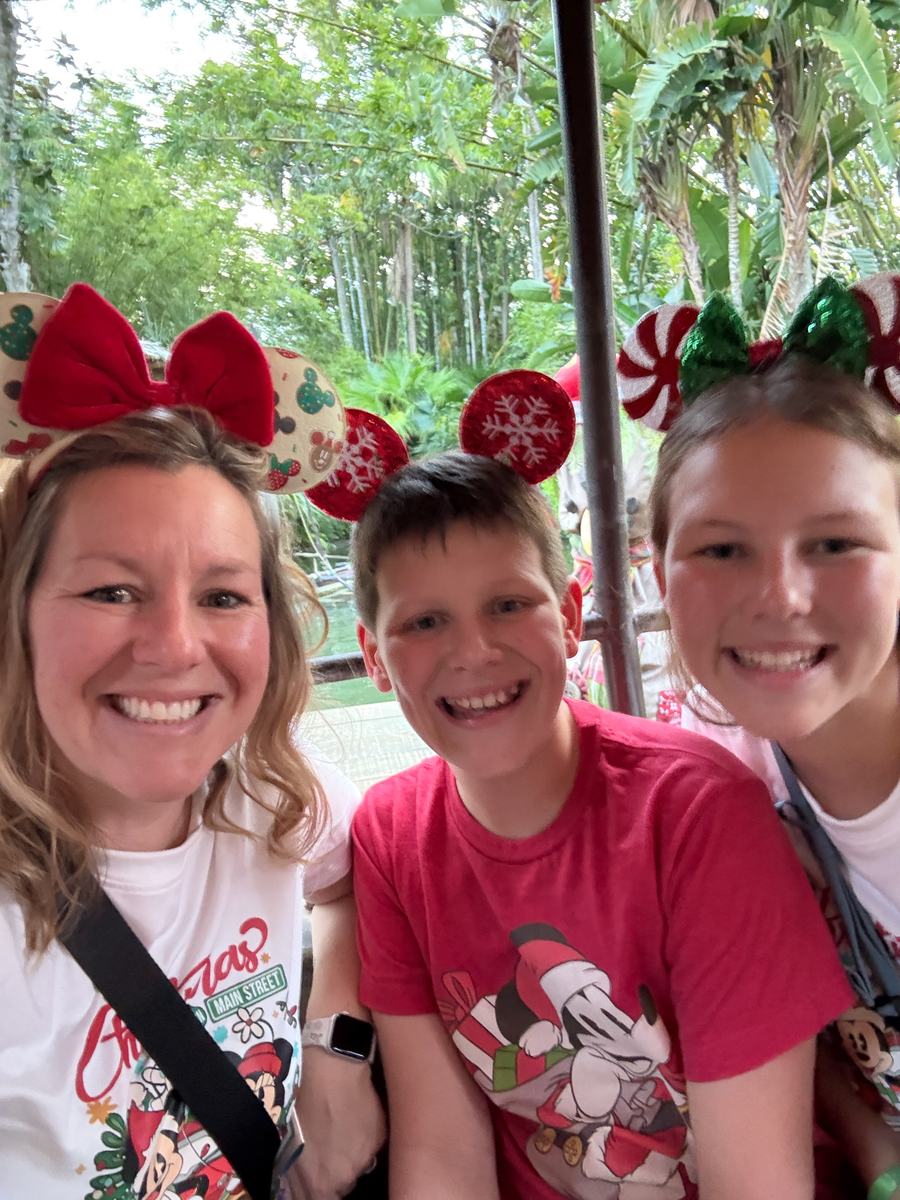 Mom and two teenagers smiling together on Jungle Cruise during a Disney Christmas trip.