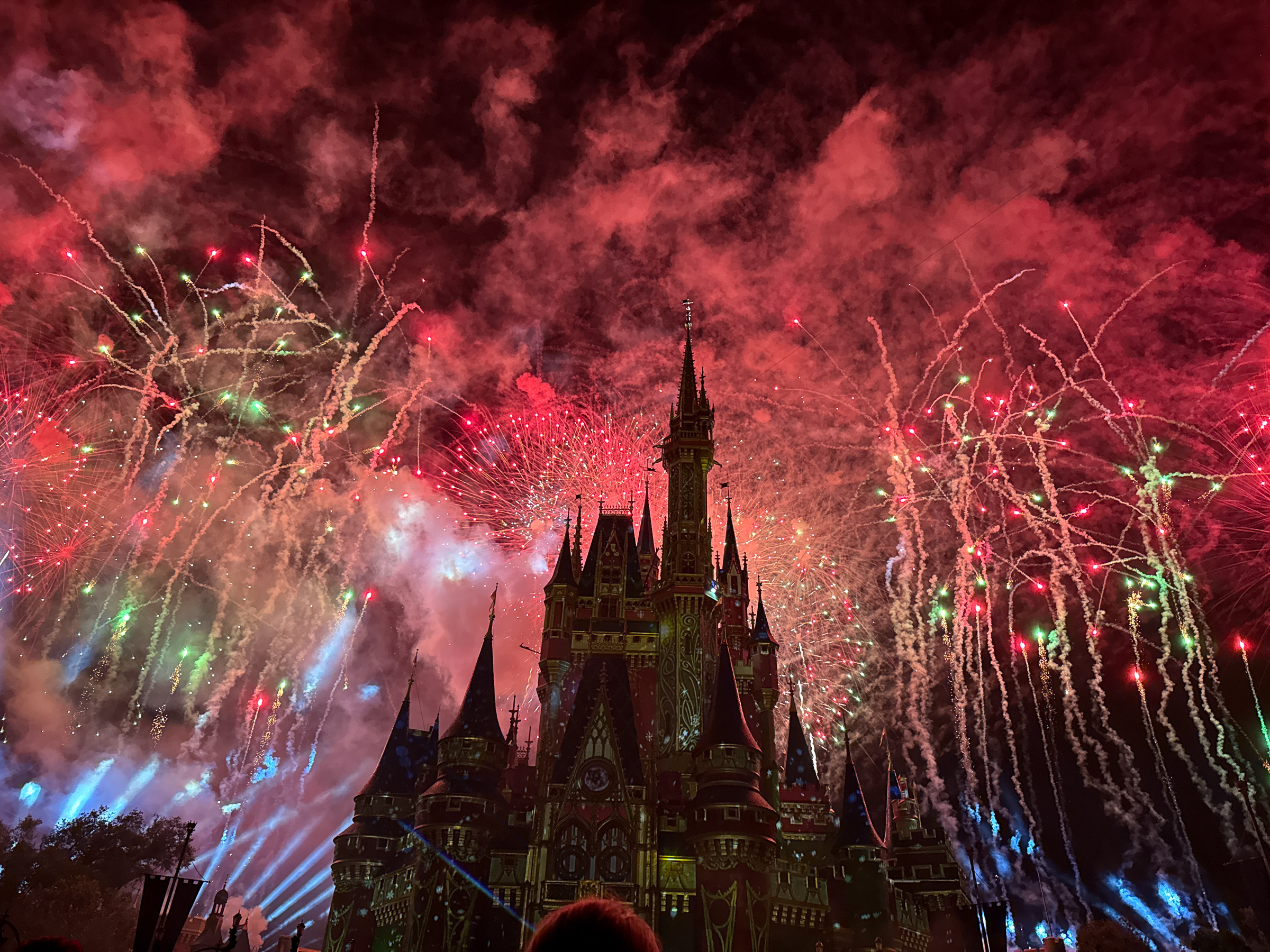 Red and green Christmas fireworks exploding around Cinderella Castle during Mickey’s Very Merry Christmas Party.